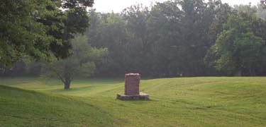 Large rolling swale with stone marker and trees on Santa Fe Trail in Kansas City, Missouri